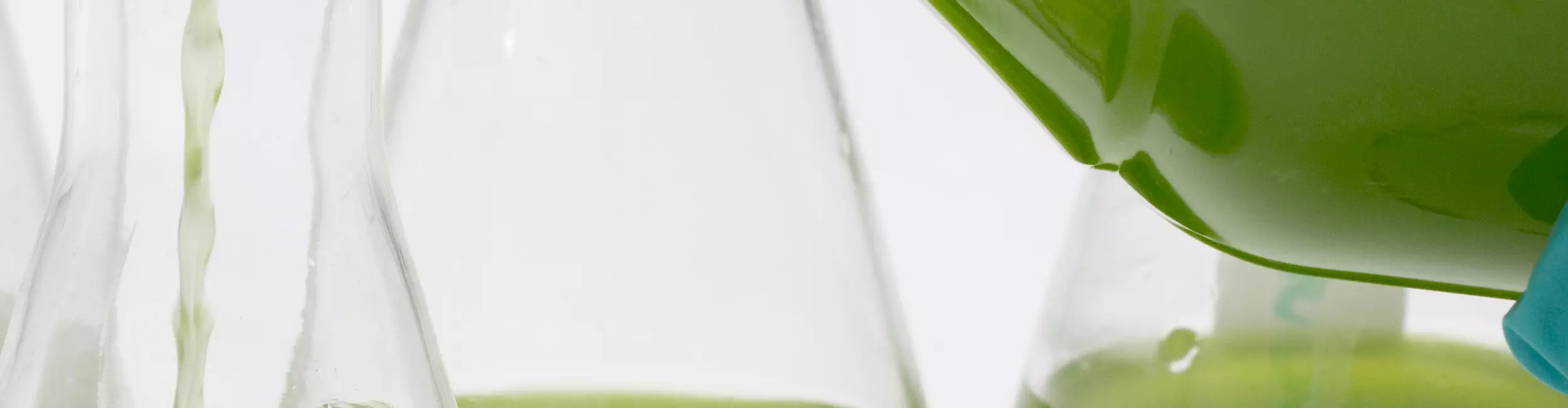 une personne versant une solution verte dans une fiole