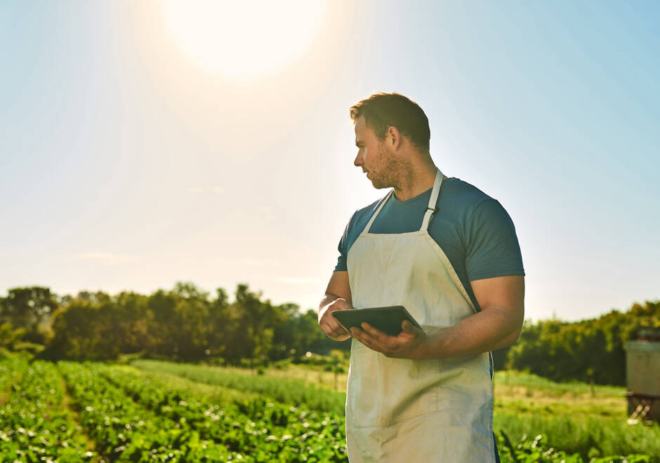 Un homme dans un champs avec une tablette dans les mains